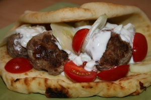 If you are using Naan, warm in a microwave for 30 seconds to soften. Add the meatballs, tzatziki sauce, cucumbers and tomatoes. Opa!