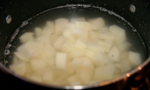 Peel and quarter potatoes. Boil in salted water until tender, about 20 minutes